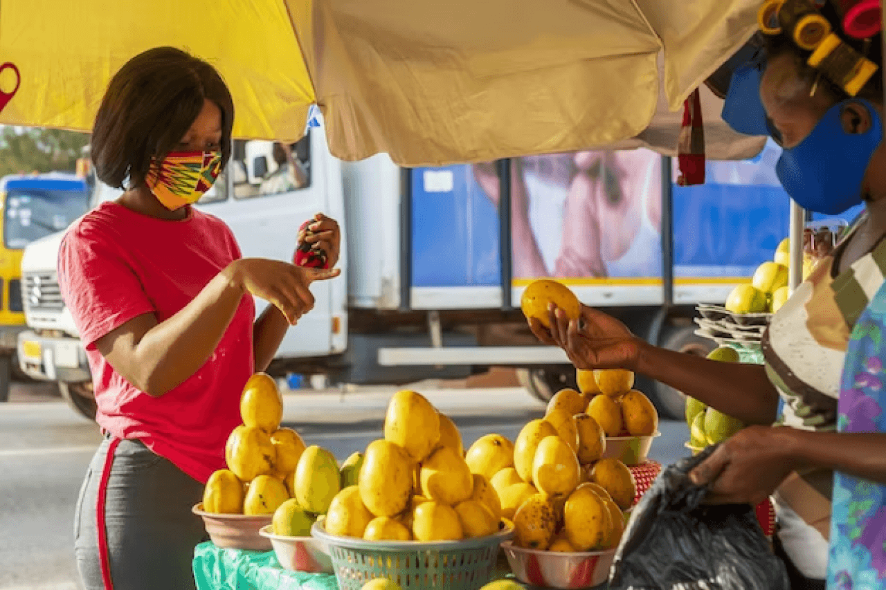 Dos señoras comercializando frutas en un carro cerca a la oficina de Fiduciaria Colmena