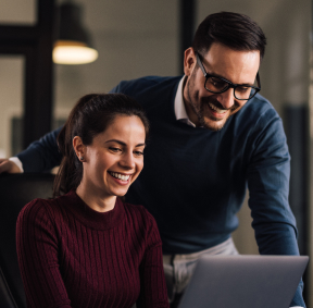 Compañeros de trabajo felices con revisando información en un computador